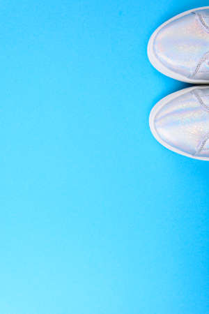 Silver sneakers on a blue background with place for text. Studio Photoの写真素材