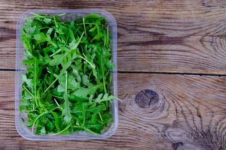 Fresh green arugula on wooden table from old boards. Photo