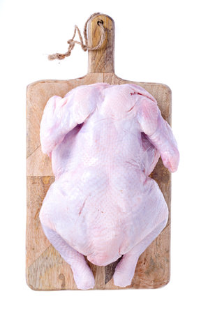 Raw chicken carcass on kitchen cutting board.の写真素材