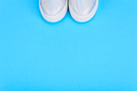 Silver sneakers on a blue background with place for text. Studio Photoの写真素材