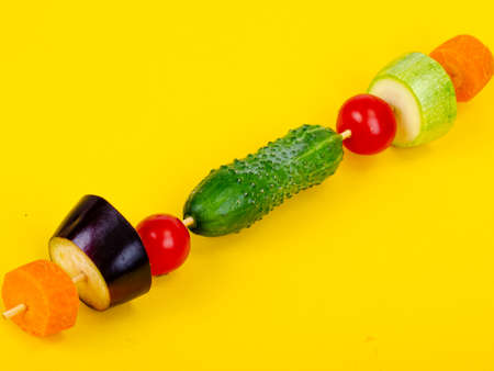 Organic fresh slises vegetables on wooden stick. Vegan or healthy food concept. Minimalistic still life on color bright background