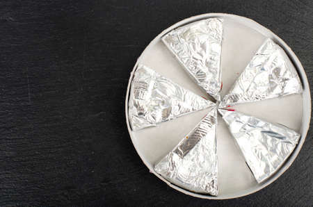Cheese triangles in foil. Studio Photo.