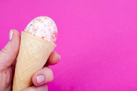 Vanilla ice cream waffle horns with decoration eggs on pink background. minimalism. Creative Easter...