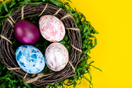 Top view of color easter haqndmade eggs and nest flatlay. Trendy minimal design spring background....