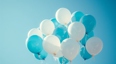 A close-up of white and blue balloons against a clear sky.の素材