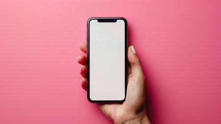 Close-up hand holding a phone with a blank white screen turned towards the camera. pink background.の素材