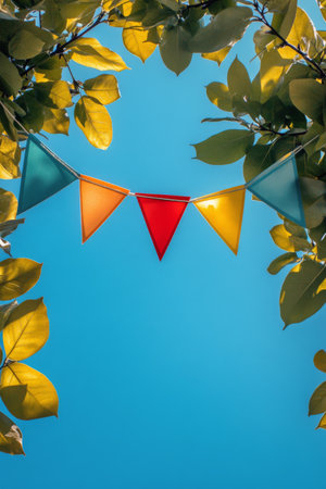 Bright fabric bunting flags in blue, pink, and orange swing gently in the breeze among green tree branches on a sunny day, creating a festive atmosphere perfect for outdoor celebrations and gatherings.の素材