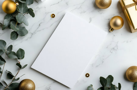 A blank greeting card is prominently placed on a marble surface, surrounded by gold ornaments, eucalyptus branches, and a wrapped gift, creating a festive atmosphere perfect for holiday greetings.の素材