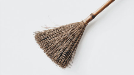 This traditional broom, crafted from natural fibers, is displayed upright against a light backdrop, showing its rustic design and practical charm. Perfect for cleaning or decoration.の素材