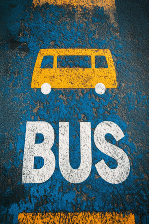 A clearly marked bus parking spot features bold white letters on an aged asphalt surface, creating a vibrant contrast. The area shows signs of wear, indicating frequent use.の素材