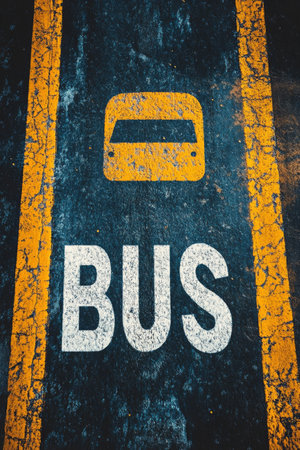 A clearly marked bus parking spot features bold white letters on an aged asphalt surface, creating a vibrant contrast. The area shows signs of wear, indicating frequent use.の素材