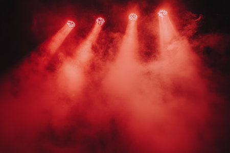 The venue is filled with red stage lights casting a vibrant glow on swirling smoke, creating an intense and captivating atmosphere for an evening show or concert performance.の素材