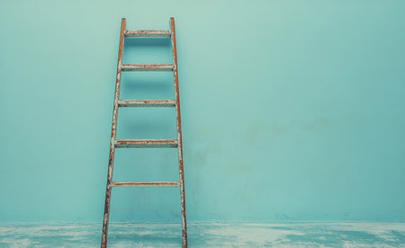 A weathered wooden ladder stands upright, leaning against a bright turquoise wall in an empty, well lit room, creating an inviting and artistic atmosphere.の素材