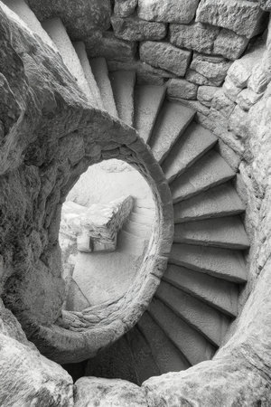 A beautifully detailed spiral staircase showcases ornate carvings and elegant curves, leading upwards through a sunlit space. The architectural design captures timeless sophistication and art.の素材