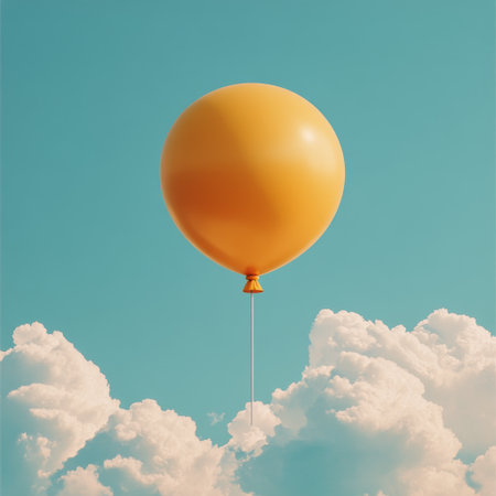A vibrant yellow balloon is suspended in the air, gently rising above soft white clouds under a clear blue sky, creating a hopeful and serene atmosphere.の素材
