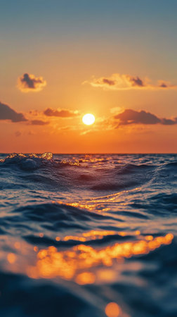 A sailboat glides across the ocean as the sun sets, casting vibrant colors in the sky and on the water, creating a peaceful and scenic atmosphere during evening hours.の素材