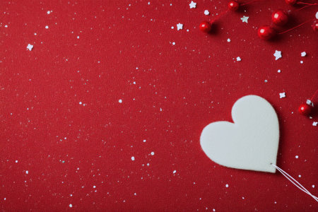 A warm red fabric serves as the backdrop, complemented by a white heart shape resting beside a textured red knit blanket. This arrangement evokes feelings of love and comfort.の素材