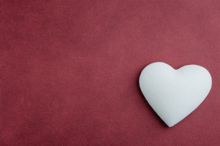 A white heart shape is placed on a bold red background, symbolizing love and affection. This simple yet striking arrangement is ideal for celebrations and romantic events.の素材