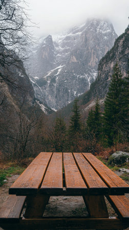 A rustic wooden table provides a perfect view of a majestic mountain landscape and lush valleys, enhancing the serene atmosphere during daylight hours.の素材