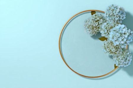 Colorful hydrangeas in shades of purple and blue are artistically arranged around a gold circular frame on a soft blue background, creating a beautiful and simple decoration..の素材
