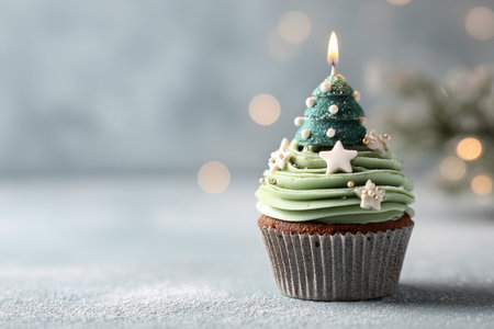 A cupcake showcases festive green icing topped with mini trees, snowflakes, and white candies. Soft candle flames add to the holiday atmosphere, creating a warm scene..の素材