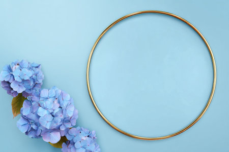 Blue hydrangeas lay gracefully beside a gold circular frame against a soft pastel backdrop, creating a calm and elegant visual.の素材