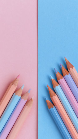 Pastel colored pencils are neatly arranged on a pink and blue background, showing their vibrant hues. These art supplies are perfect for drawing and coloring.の素材