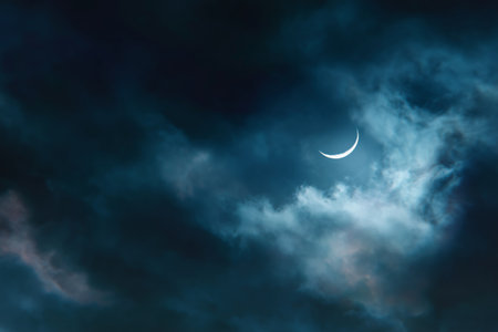 In the dark night sky, a thin crescent moon is visible among wispy clouds, casting a gentle light. The atmosphere is tranquil, with hints of blue and gray shades.の素材