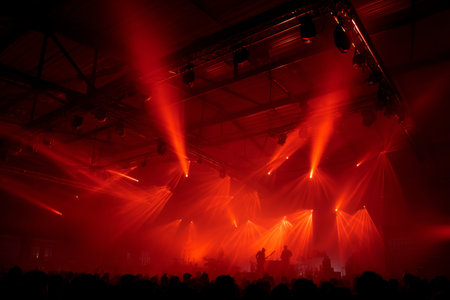 Colorful red lights create a vibrant atmosphere at an indoor concert. The crowd enjoys the music while silhouettes of performers are seen on stage, immersed in the energy of the night.の素材