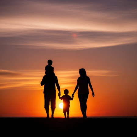 A heartwarming image of a family of four standing on a beach at sunset. The parents hold the hands of their two children, creating a beautiful silhouette against the vibrant orange and yellow sky. The sun is setting on the horizon, casting a warm glow over the scene. The family appears to be enjoying a peaceful and memorable moment together.の素材