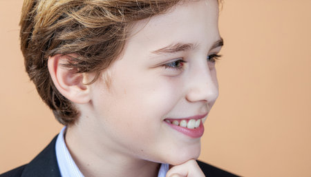 Young child radiating kindness slight chin tilt clamshell light on pastel peach set warm studio portrait for wellness caregiving inclusive education and advertisingの素材