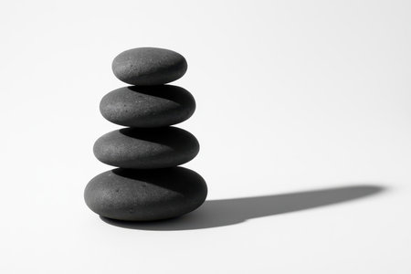 Balanced stack of flat basalt stones forming a minimal tower on whiteの素材
