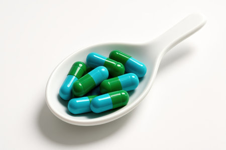Blue and green medicine capsules in matte white ceramic spoon placed diagonallyの素材