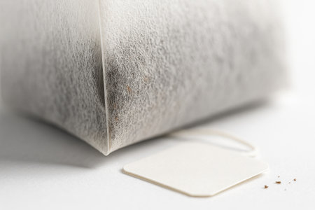Extreme close up of the crimped seam and corner of a paper tea bag with tack sharp edge and visible tea particles studio isolated on whiteの素材