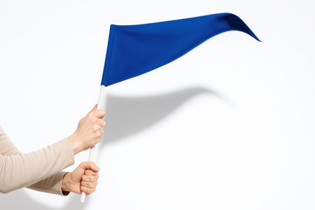 Cropped arms swinging a plain blue pennant on a slim pole dynamic gesture studio isolated on whiteの素材