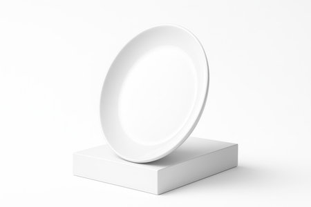 Empty circular white ceramic plate displayed on a low white acrylic block minimal product studio isolated on whiteの素材