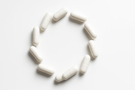 Spiral ring of white medicine capsules suspended around an empty center as if orbiting clean pharmaceutical concept studio on whiteの素材