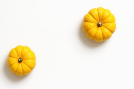 Top down two yellow pumpkins placed diagonally across the frame leaving wide negative space clean autumn produce flat lay on whiteの素材