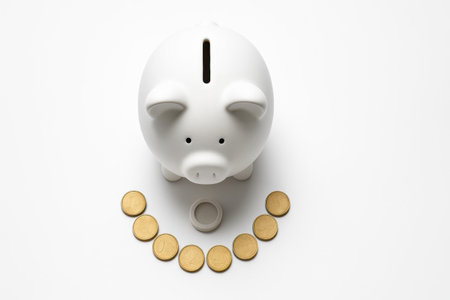 White piggy bank top down with the stopper removed and a neat semicircle of coins arranged around the base clean studio on whiteの素材
