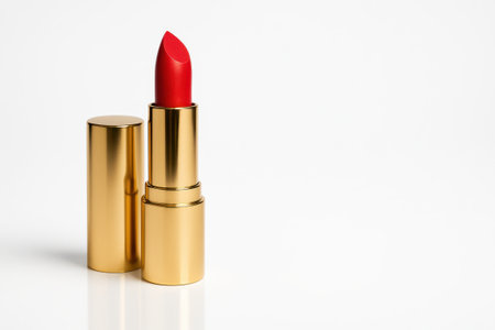 Red lipstick in a gold tube front three quarter hero angle with cap removed standing upright on whiteの素材