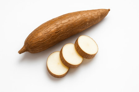 Whole cassava with three slices top down flat lay with the tuber placed diagonally and the white interior clearly visible on whiteの素材