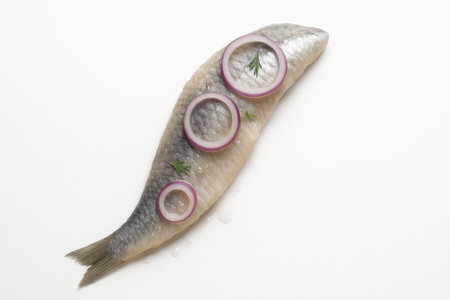 Marinated herring fillet gentle s curve with thin red onion rings on white background isolated seafood appetizer top view for Nordic cuisine recipe and menu designの素材