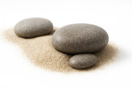 Rock stones on sand macro of two half buried pebbles with crisp grains on white background for geology texture nature and background themesの素材