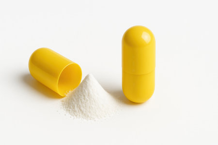 Two yellow drug capsules one opened spilling fine white powder cone on white background for medicine pharmacy healthcare and risk themesの素材