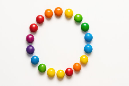Assorted colorful round candies top down on white background arranged in even circular ring with clean empty center for sweets pattern and design themesの素材