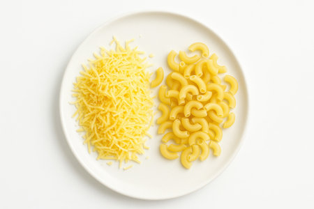 Top down food photo of grated cheese pile beside dry pasta on white plate comfort meal ingredient concept for italian recipe card restaurant menu and home cooking designの素材