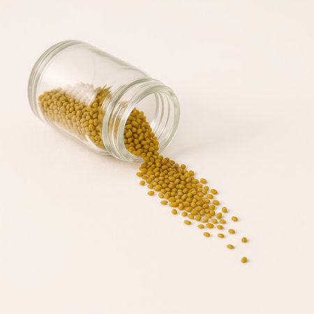 Dry alfalfa seeds lined inside clear glass jar lying on side with seeds spilling in natural trail across white surface agriculture sprouting superfood and vegan nutrition conceptの素材