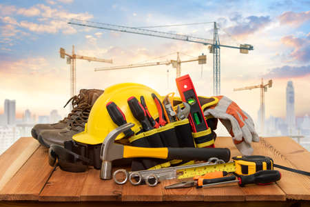Yellow helmet for construction work and tools with a background crane.