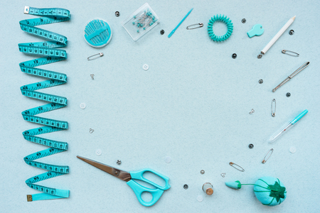 Sewing kit on a blue background. Scissors, tape, pins, needles, ripper, buttons, buttons thimble weight crayon pencil View from aboveの写真素材