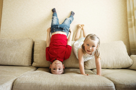 Brother and sister playing on the couch: the boy stands upside down.の写真素材